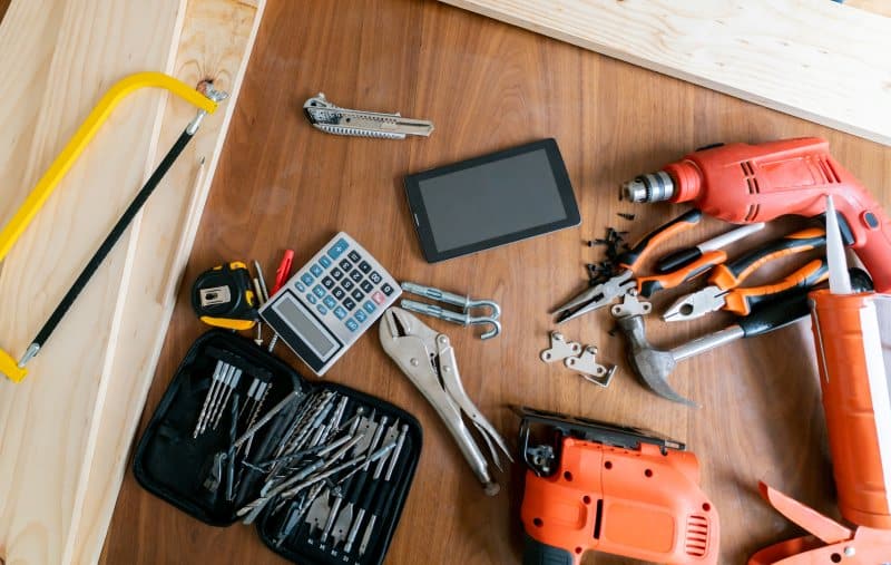 Construction tools including drill pliers bits measuring tape on wooden surface
