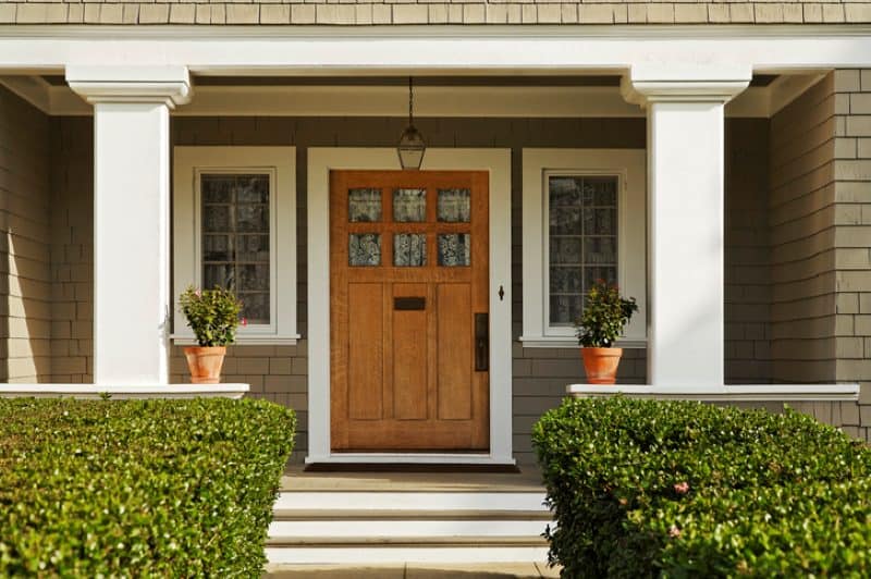 Wood front entry door with sidelights and porch columns on a traditional home