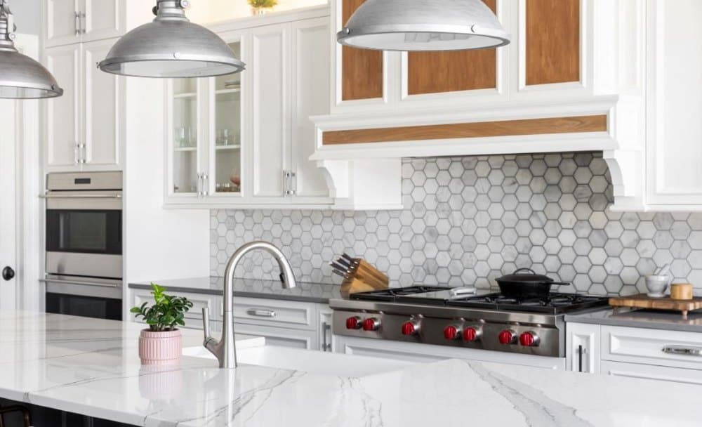 Modern kitchen with white cabinets quartz island hex tile backsplash and stainless range