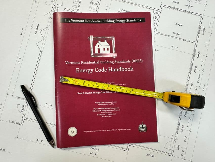 Vermont residential building energy code handbook with tape measure on blueprint